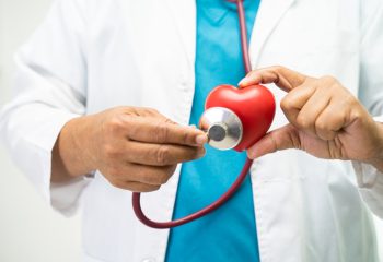 doctor auscultando un corazón rojo de plástico