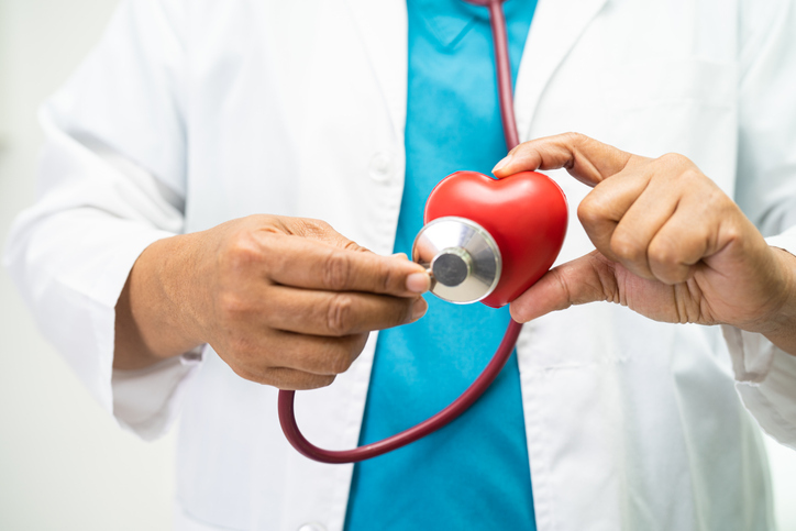 doctor auscultando un corazón rojo de plástico